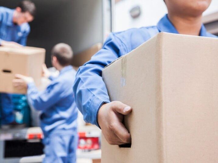 team of local movers carrying heavy furniture down a flight of stairs